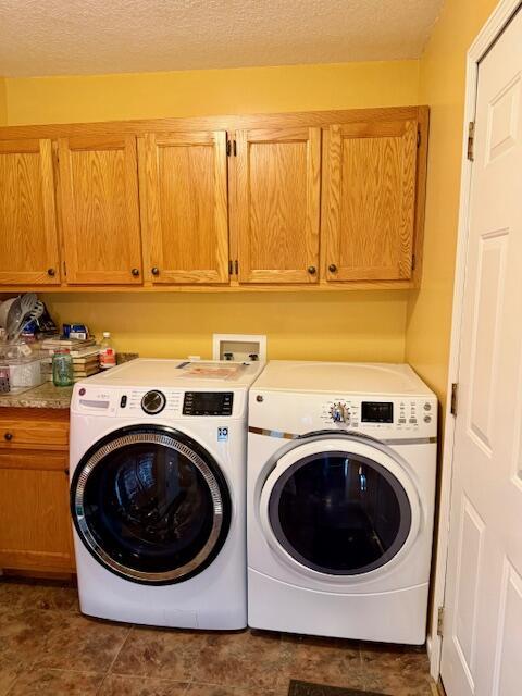 laundry room with cabinets, washer and dryer, and a textured ceiling