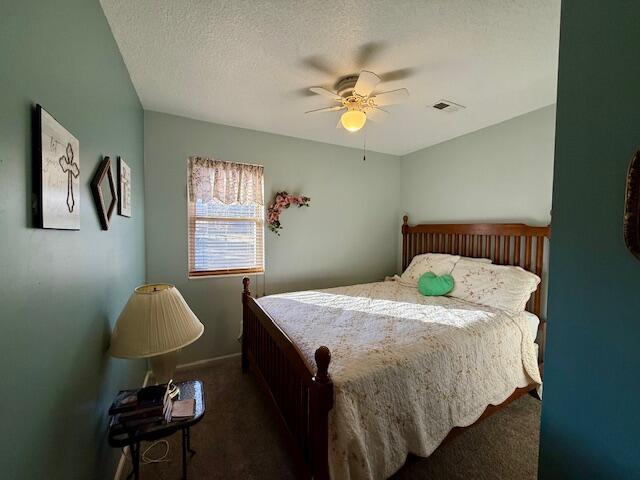 carpeted bedroom featuring ceiling fan and a textured ceiling