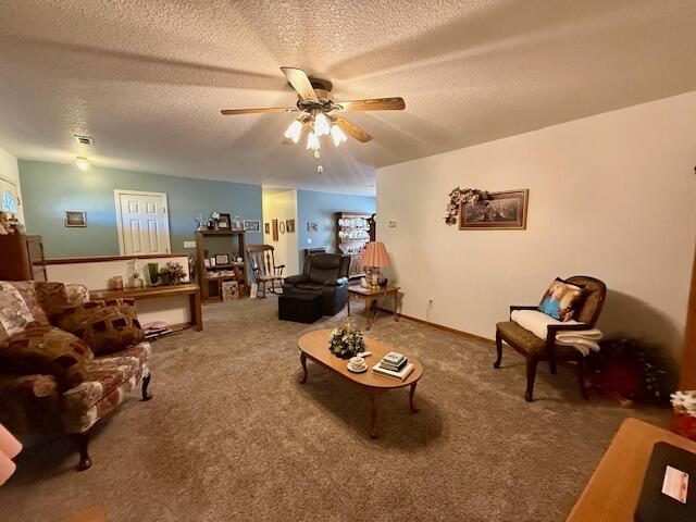 living room with a textured ceiling, ceiling fan, and carpet