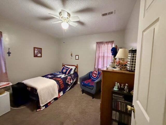 bedroom featuring ceiling fan, a textured ceiling, and carpet