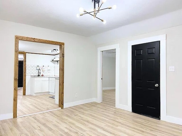 unfurnished bedroom featuring a notable chandelier, a walk in closet, light hardwood / wood-style flooring, and a closet