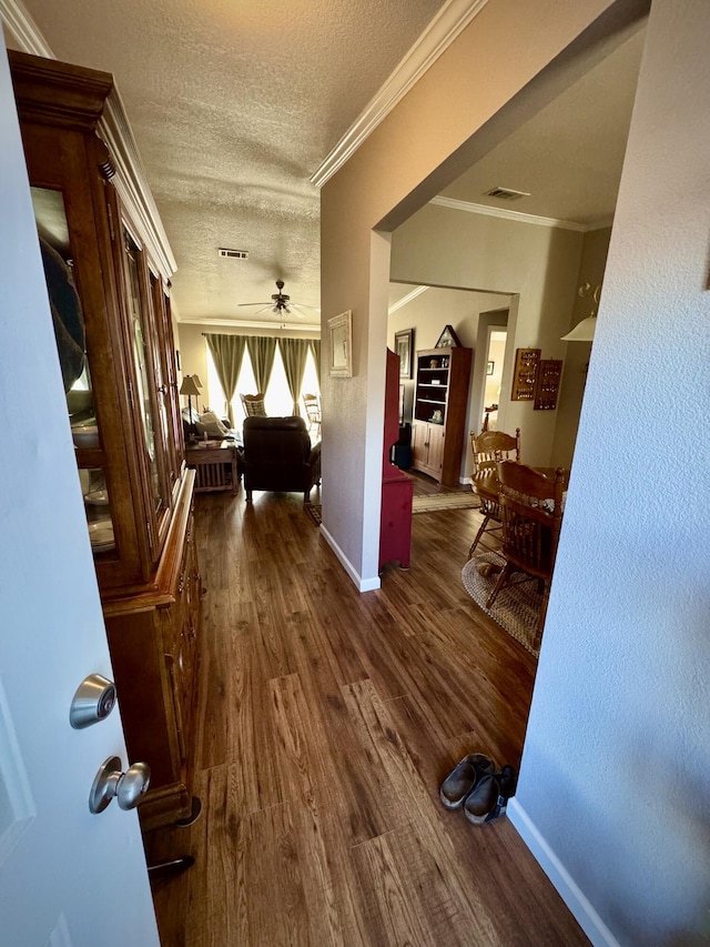 hall with crown molding, dark hardwood / wood-style floors, and a textured ceiling