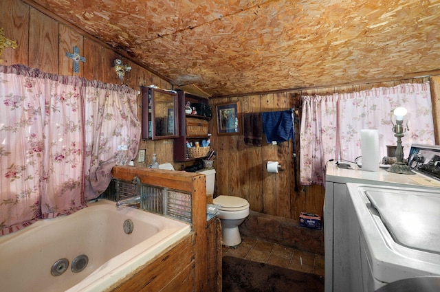 bathroom with toilet, washer / dryer, wood walls, vaulted ceiling, and a tub