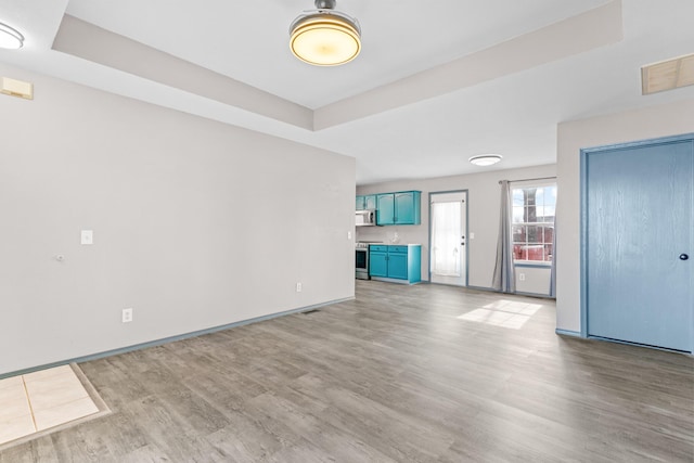 unfurnished living room with a raised ceiling and light hardwood / wood-style floors