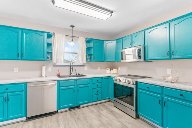 kitchen with blue cabinets, sink, decorative light fixtures, light wood-type flooring, and stainless steel appliances