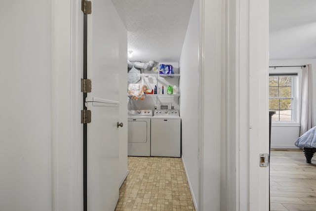 laundry area with washer and clothes dryer and a textured ceiling