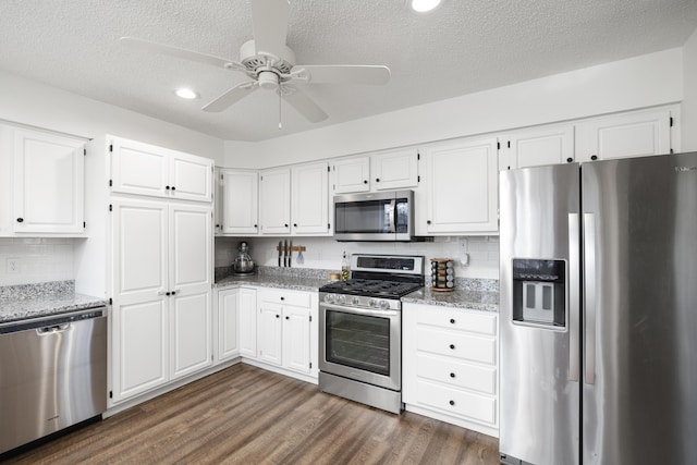 kitchen with stainless steel appliances, white cabinetry, light stone countertops, and dark hardwood / wood-style floors