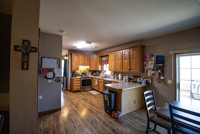 kitchen with appliances with stainless steel finishes, sink, light wood-type flooring, and kitchen peninsula