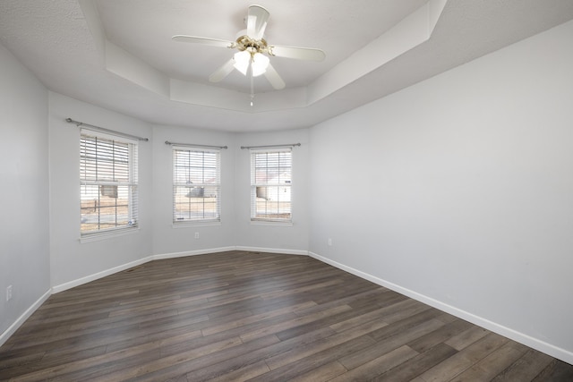 unfurnished room with dark hardwood / wood-style flooring, a tray ceiling, and ceiling fan