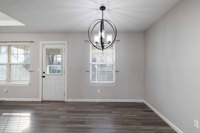 unfurnished dining area with dark hardwood / wood-style flooring and a notable chandelier