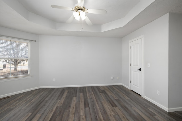 unfurnished room with dark wood-type flooring, ceiling fan, and a tray ceiling