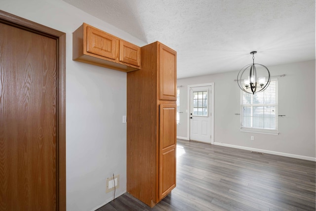 kitchen with pendant lighting, dark wood-type flooring, a chandelier, and a textured ceiling