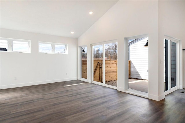 spare room with plenty of natural light, dark wood-type flooring, and high vaulted ceiling