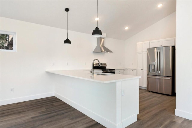 kitchen with appliances with stainless steel finishes, white cabinetry, hanging light fixtures, kitchen peninsula, and wall chimney range hood