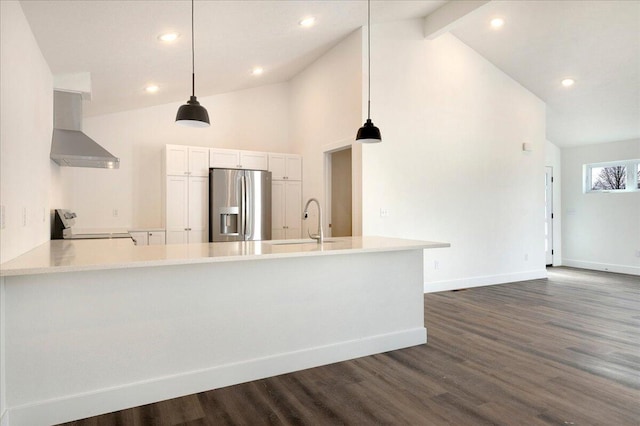 kitchen featuring stove, stainless steel refrigerator with ice dispenser, white cabinets, kitchen peninsula, and wall chimney exhaust hood