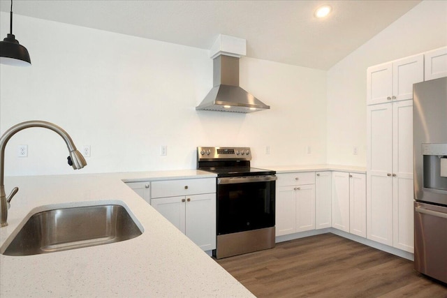 kitchen featuring appliances with stainless steel finishes, decorative light fixtures, range hood, sink, and white cabinets