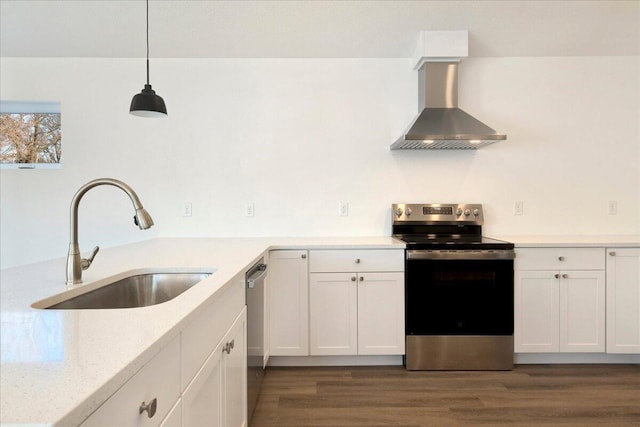 kitchen with sink, light stone counters, appliances with stainless steel finishes, pendant lighting, and wall chimney range hood