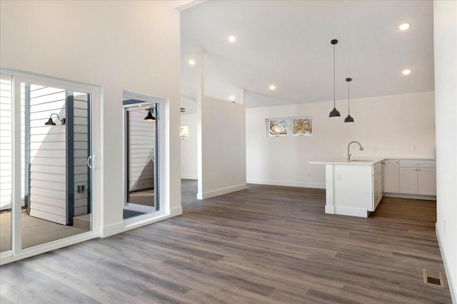 interior space featuring pendant lighting, high vaulted ceiling, white cabinetry, sink, and dark wood-type flooring