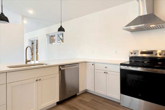 kitchen with sink, island range hood, hanging light fixtures, and appliances with stainless steel finishes