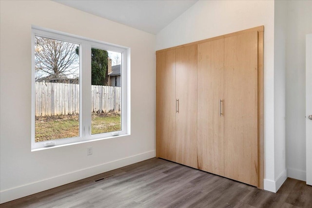 unfurnished bedroom with lofted ceiling, hardwood / wood-style flooring, and a closet