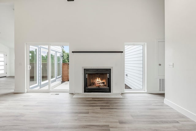3481 W Moark St, Springfield, MO 65810 - unfurnished living room featuring a high ceiling, wood finished floors, plenty of natural light, and a fireplace with flush hearth