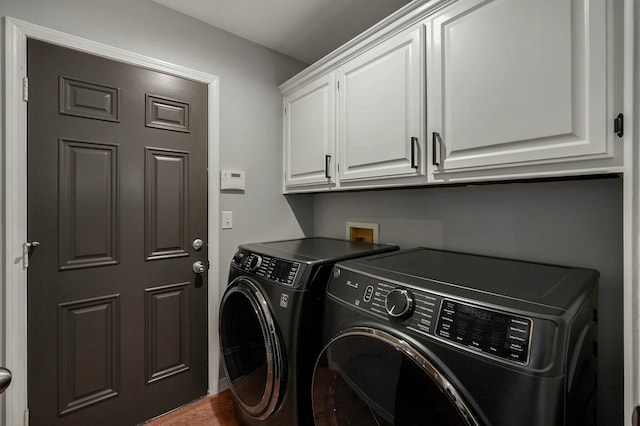 clothes washing area featuring separate washer and dryer, hardwood / wood-style flooring, and cabinets