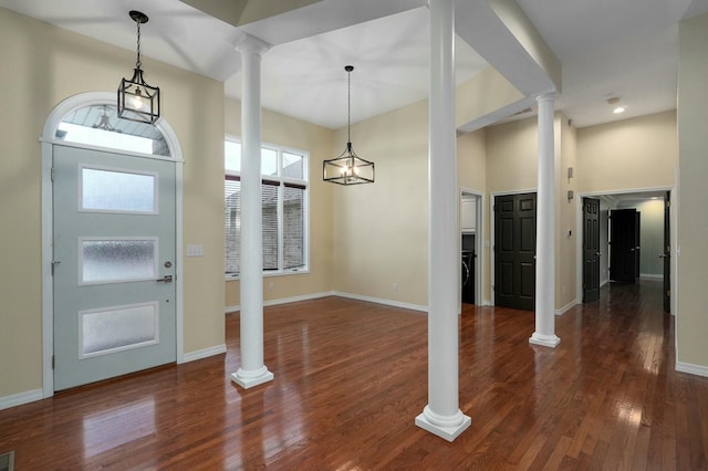 entrance foyer with dark hardwood / wood-style flooring, decorative columns, and a high ceiling