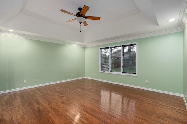 spare room with a tray ceiling, wood-type flooring, ornamental molding, and ceiling fan