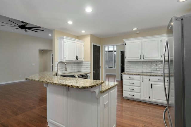 kitchen with stainless steel fridge, light stone countertops, sink, and white cabinets