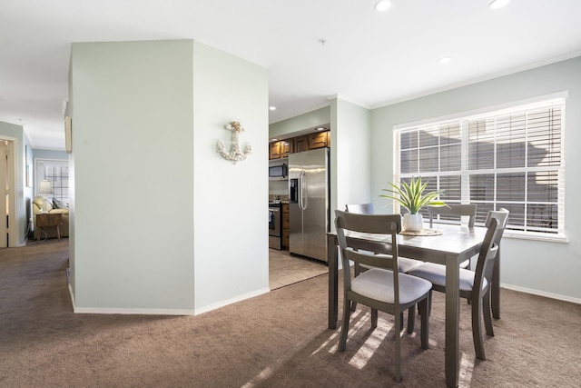 carpeted dining space with crown molding