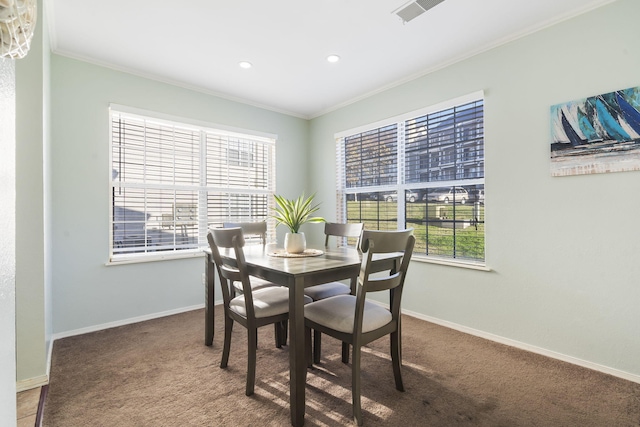 carpeted dining room featuring crown molding