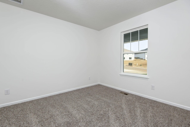 carpeted empty room featuring a textured ceiling