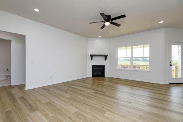 unfurnished living room with ceiling fan, a fireplace, light hardwood / wood-style floors, and a wealth of natural light