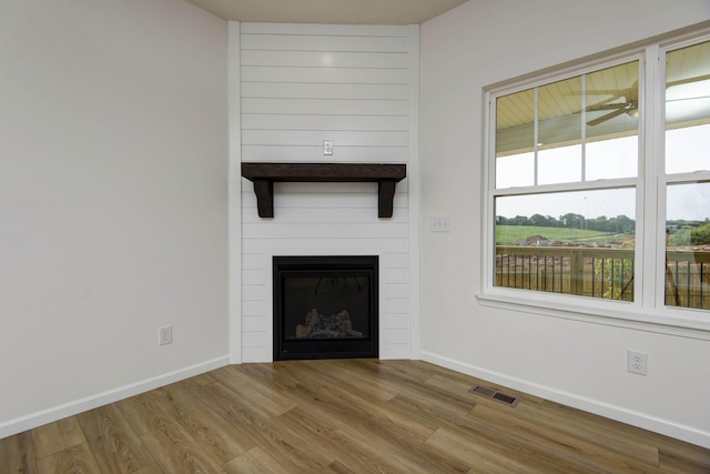 unfurnished living room featuring ceiling fan, a fireplace, and light hardwood / wood-style flooring