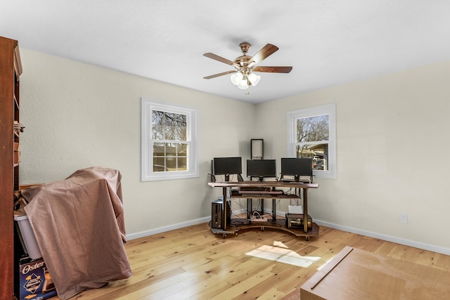 home office with light hardwood / wood-style floors and ceiling fan