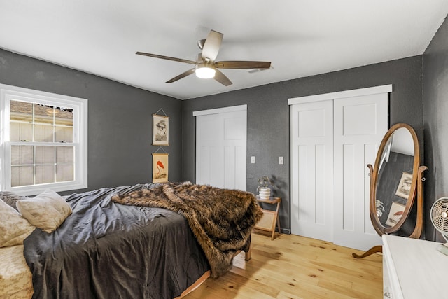 bedroom with ceiling fan, two closets, and light wood-type flooring