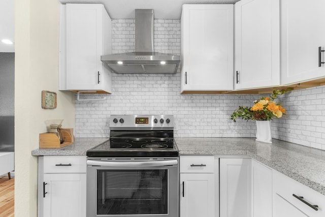 kitchen featuring light stone counters, white cabinets, stainless steel electric stove, and wall chimney exhaust hood