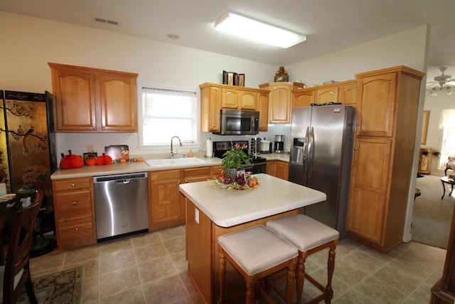 kitchen featuring sink, a breakfast bar area, a center island, light tile patterned floors, and stainless steel appliances