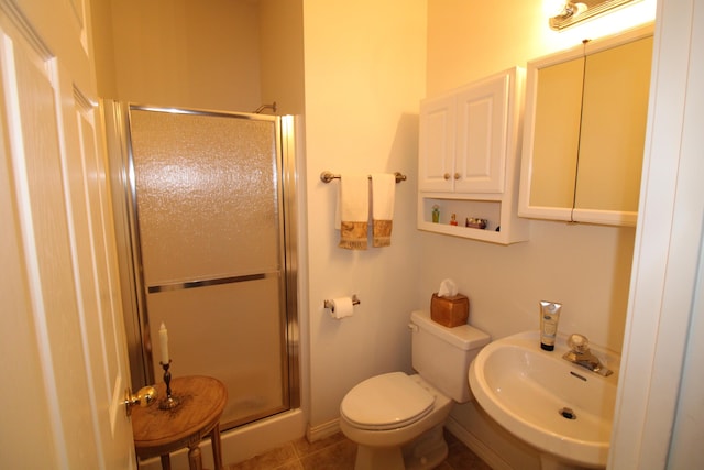 bathroom featuring toilet, tile patterned floors, a shower with door, and sink