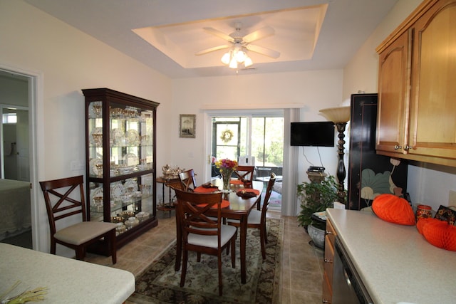 dining room with tile patterned flooring, ceiling fan, and a tray ceiling