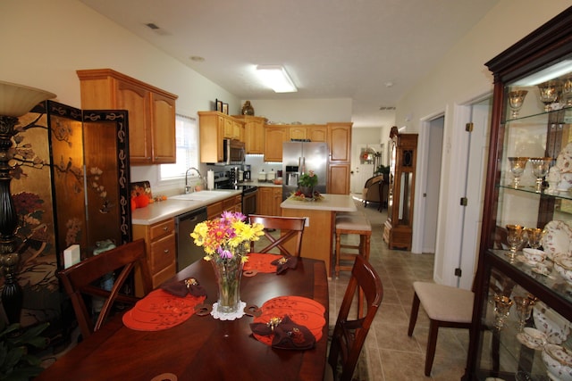 interior space featuring light tile patterned floors, sink, stainless steel appliances, a center island, and a kitchen breakfast bar