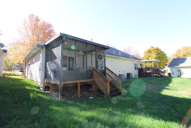 rear view of house featuring a wooden deck, a sunroom, a yard, and central AC unit