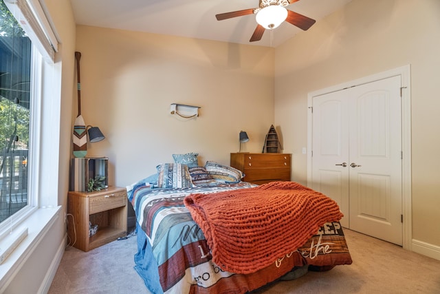 bedroom with ceiling fan, light carpet, and a closet