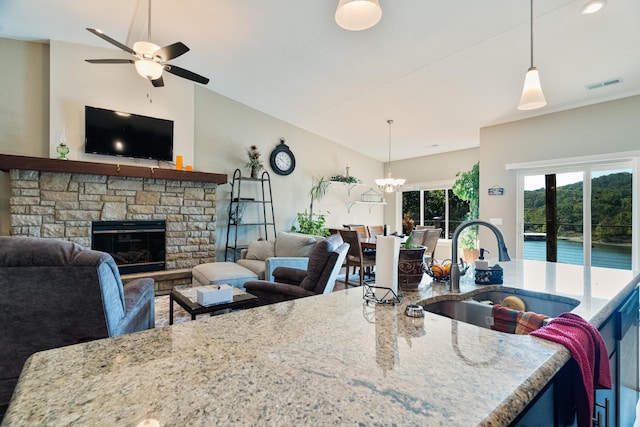 kitchen with light stone counters, sink, pendant lighting, and a fireplace