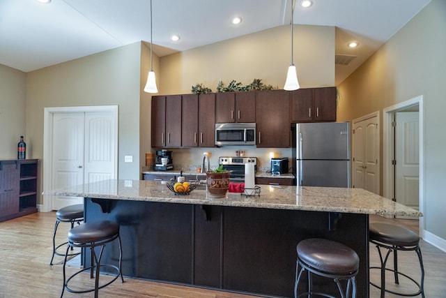 kitchen featuring dark brown cabinetry, a center island with sink, and appliances with stainless steel finishes