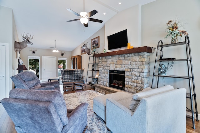 living room with lofted ceiling, a stone fireplace, light hardwood / wood-style floors, and ceiling fan