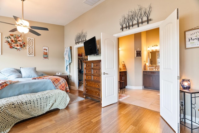 bedroom featuring hardwood / wood-style floors, a walk in closet, ceiling fan, ensuite bath, and a closet