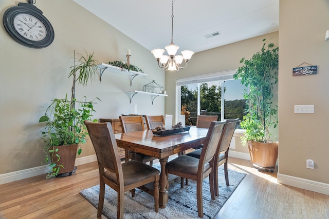 dining area with light hardwood / wood-style floors and a chandelier