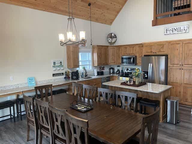 dining room featuring high vaulted ceiling, sink, dark hardwood / wood-style flooring, wooden ceiling, and an inviting chandelier