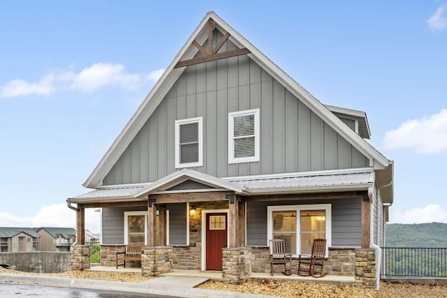 view of front facade with stone siding, board and batten siding, and covered porch